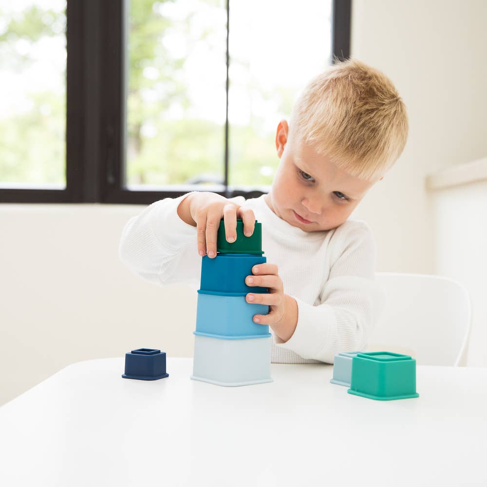 Front view of a child creating a tower with the Cool Blue Happy Stacks.