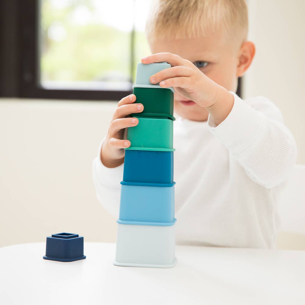 Front view of a young child making a tower stack with the Cool Blue Happy Stacks.