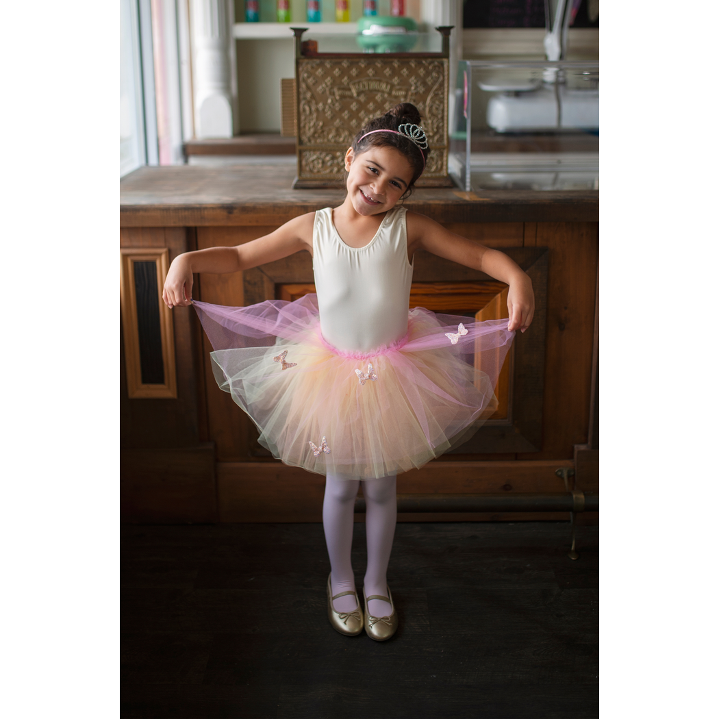 Girl with tiara and ballet shoes sitting on a counter wearing butterfly skirt