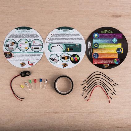 Contents of the Torch Light kit, with five colored lights, are spread out on a table.