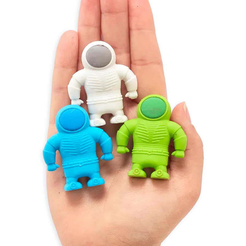 Front view of blue, white, and green astronaut erasers in the palm of a person&#39;s hand.