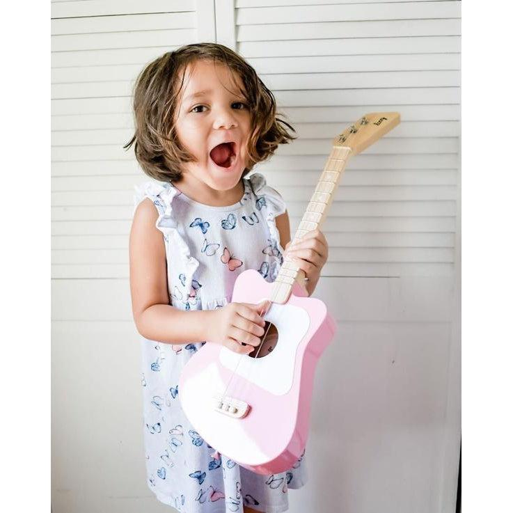 Front view of a child holding the mini pink guitar.