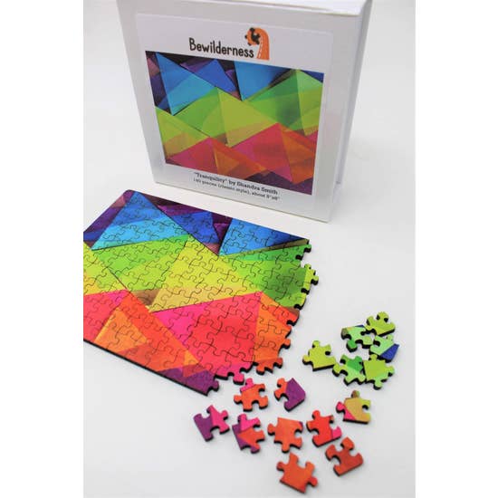 Puzzle box with partially assembled puzzle featuring translucent, rainbow-colored, overlapping triangles.