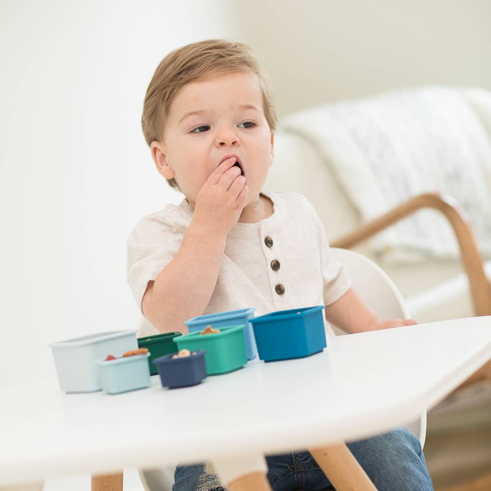 Front view of a child eating from the food he has in his Cool Blue Happy Stacks.