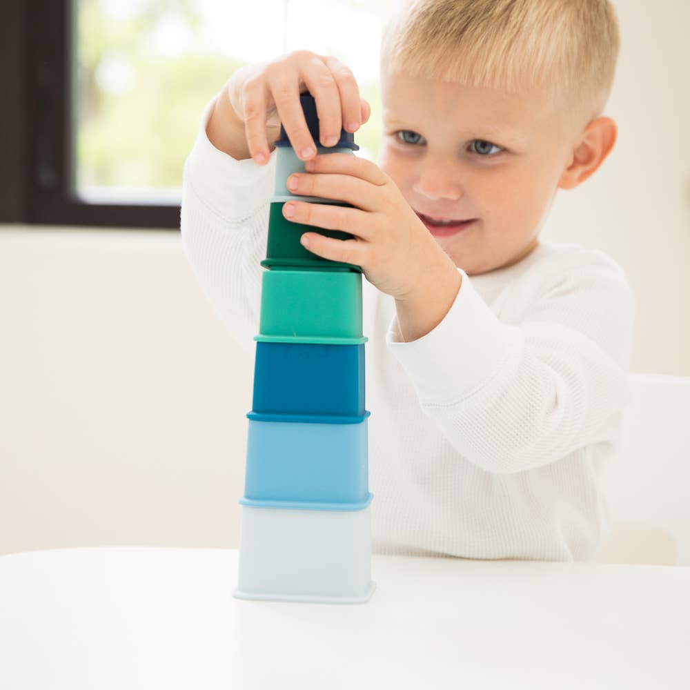 Front view of a child putting the final piece on his tower with Cool Blue Happy Stacks.