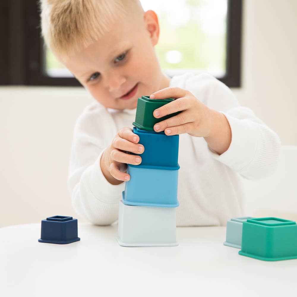 Front view of a child building a tower with the Cool Blue Happy Stacks.
