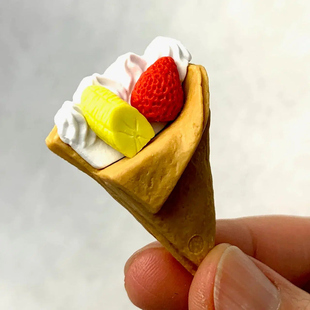 Front view of a person&#39;s fingers holding the dessert pizza from the Puzzle Eraser Card Set-Dessert.