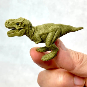 Front view of a person's fingers holding the green T Rex Dinosaur Eraser.
