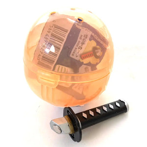 Front view of orange capsule with black and silver sword from the Samurai Katana Sword Magnet Capsule.