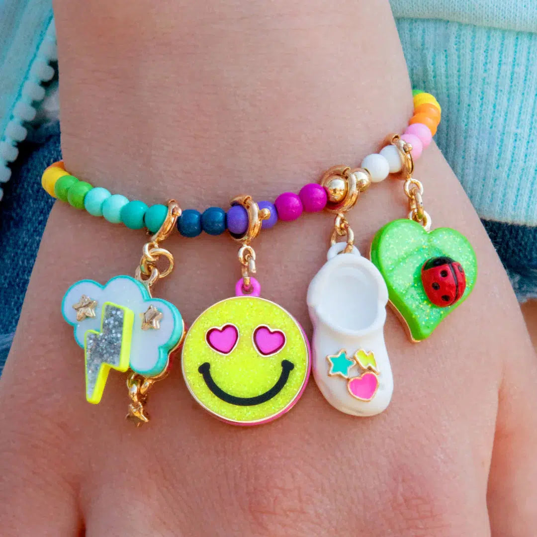 Front view of a hand wearing the glitter smiley face charm on a charm bracelet.