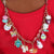 Front view of a person wearing a red sweater and a charm necklace with the Charm It-Gold Unicorn Smoothie Charm on it. 