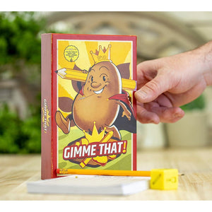 Front view of person holding up the Gimme That! Game box and the score sheet, pencil, and die in front of it.