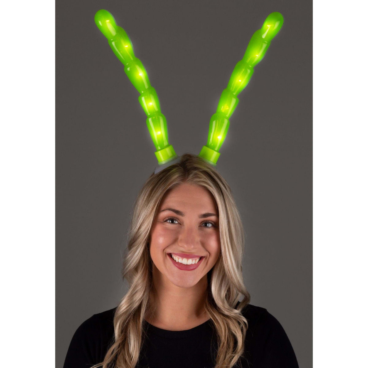 Front view of a woman wearing the Light-Up Green Insect Antennae Lumen Horns showing them lit up.