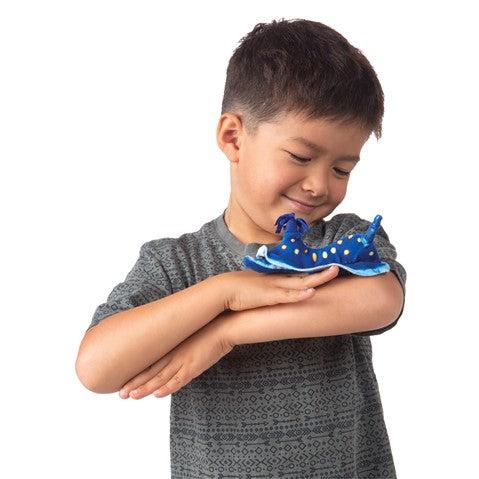 Front view of a young boy holding the Mini Nudibranch-Blue-Finger Puppet on the crook of his arm.