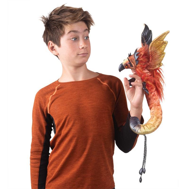 Front view of a young boy holding and looking at the Phoenix-Hand &amp; Wrist Puppet.