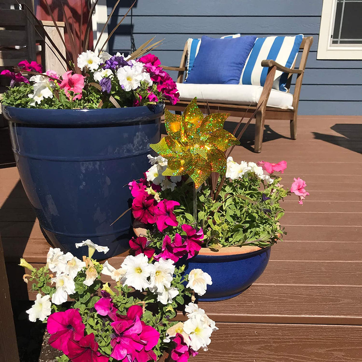 Front view of a porch showing the Gold Mylar Pinwheel in a planter with flowers.