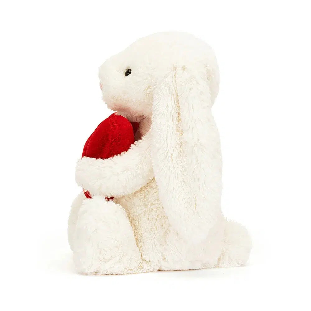 Left side view of Jellycat Bashful Red Love Heart Bunny 12&quot; holding the red heart.