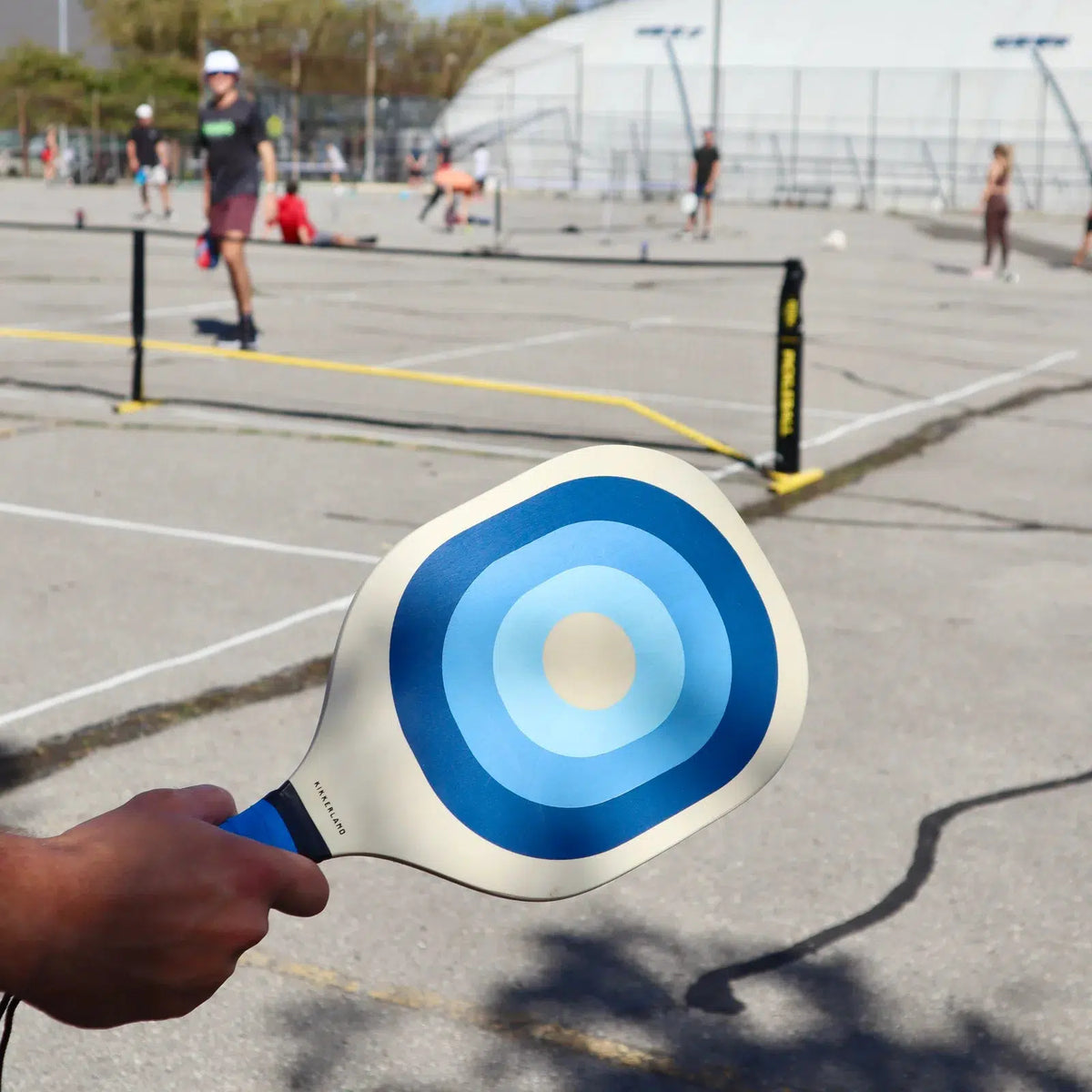 Front view of a court where a person is playing pickleball with the blue paddle from the Pickleball set in their hand.