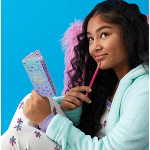 Front view of a young girl holding the mini journal from the DIY Sweet Dreams kit.