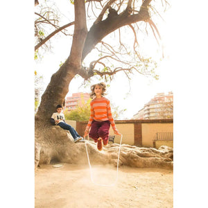 Front view of a young child jumping with the coral Wooden Jump Rope.