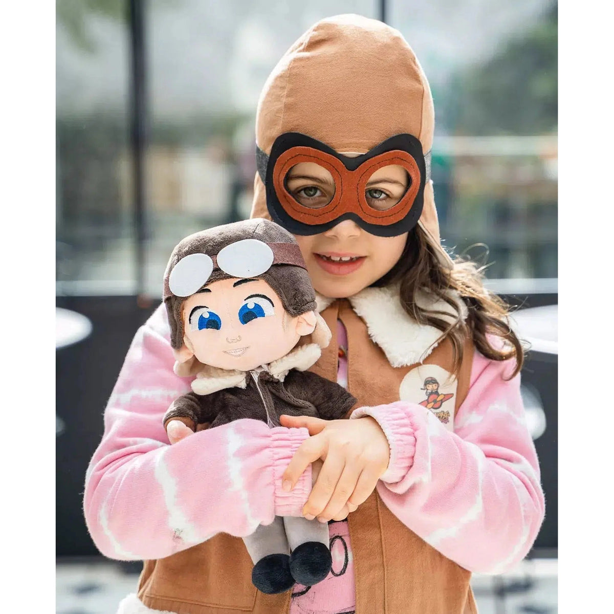 Front view of a young girl holding theAmelia Earhart-Doll-12 Inch.