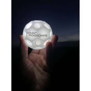 Front view of a person's hand holding a lit up Moonshine Ball.