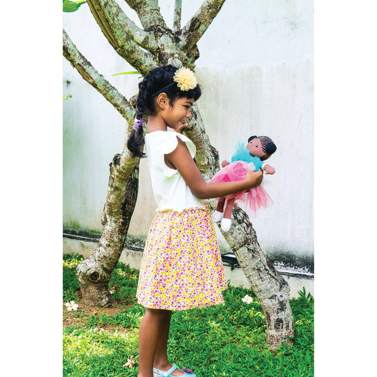 Front view of a girl outside holding the Kessie with Two Special Outfits - 15 inches.