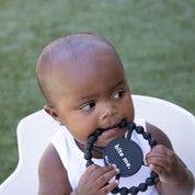 Front view of a baby biting on the Bite Me Happy Teether.