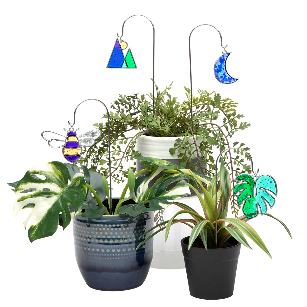 A grouping of four plants, each with a plant charm hanging on a mini-shepherds hook, decorating the plants.