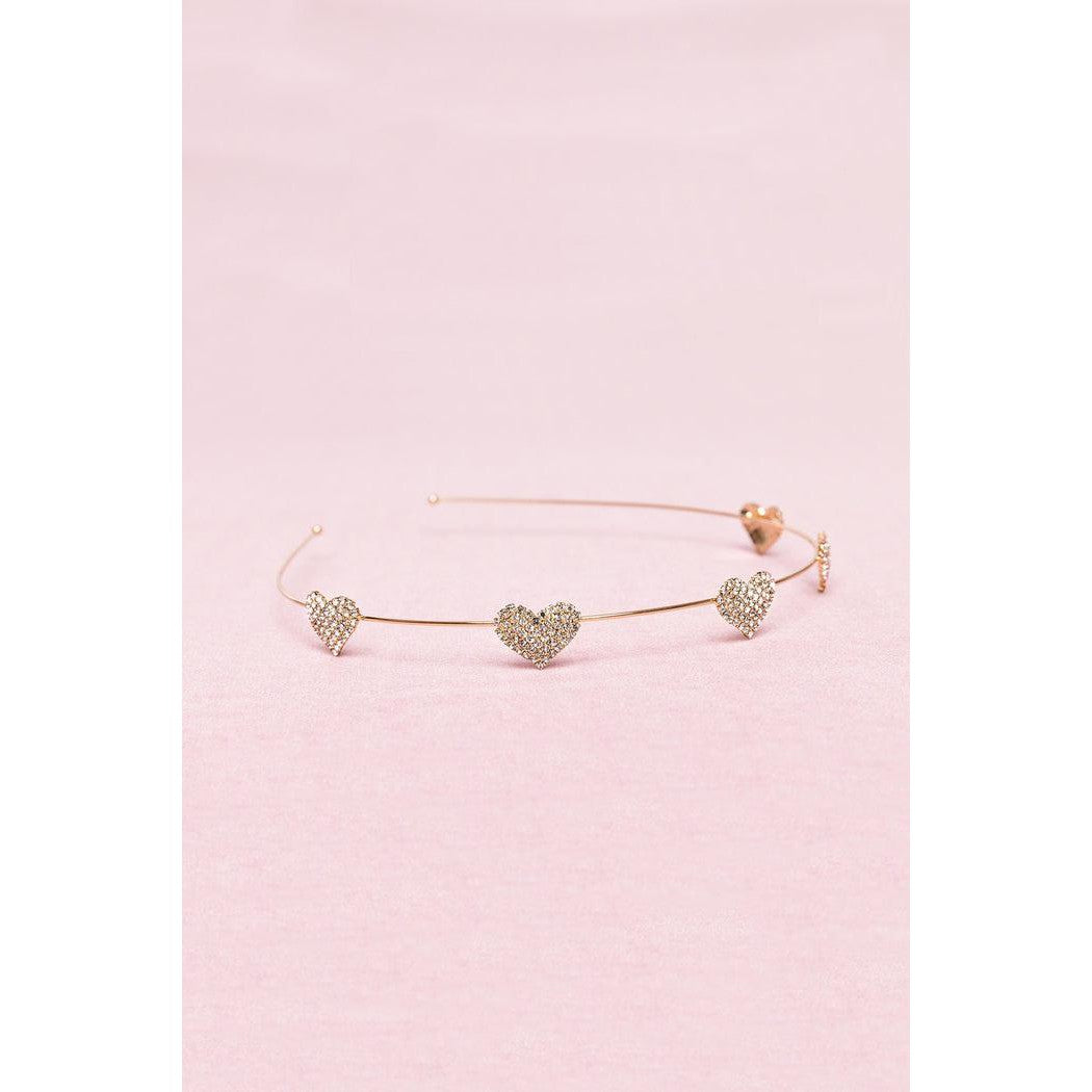 Thin gold wire headband with rhinestone hearts spaced along it.