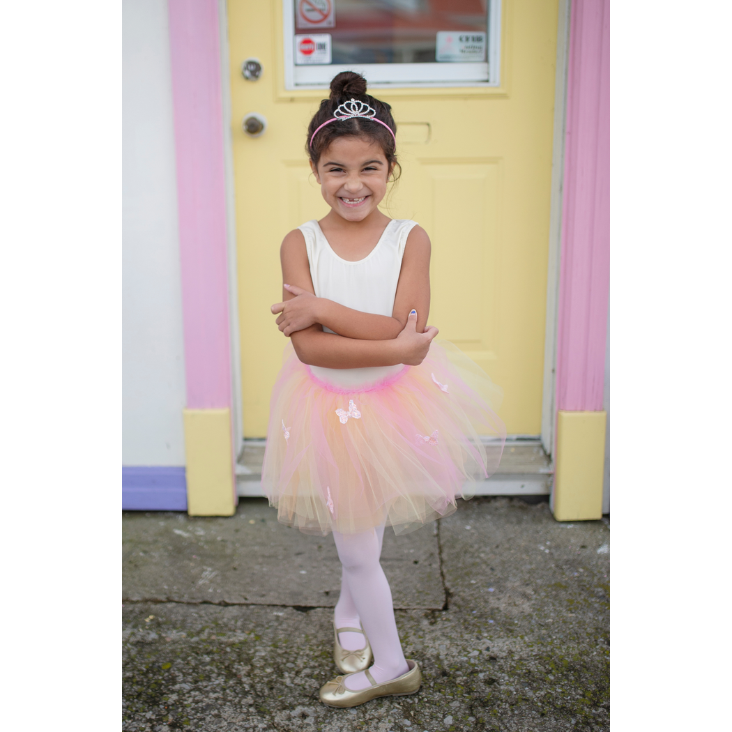 Girl with tiara and ballet shoes in fifth position wearing butterfly skirt