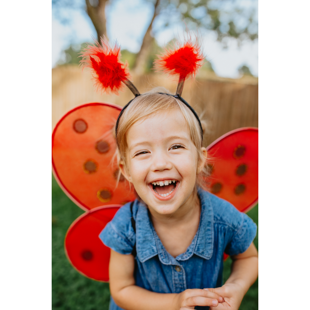 Smiling girl, front view of ladybug wings and headband