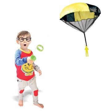 Front view of a child playing with a parachute launcher, he is holding a launcher in one hand as he watches the parachutist descent.