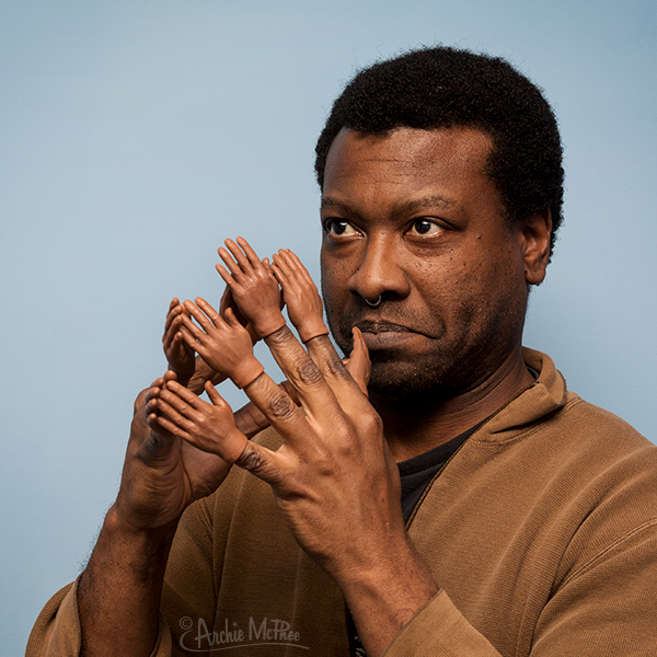 Front view of a man with the darker skin tone Finger Hands puppets on each hand.