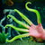 Front view of a hand with Glow Tentacles on it against a green background.