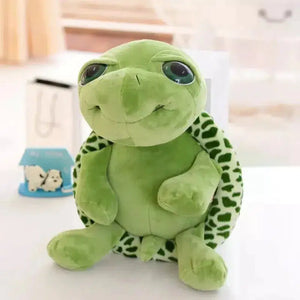 Green plush turtle sitting up. It has big eyes and a large smile