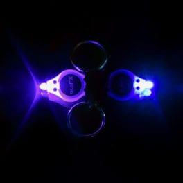 Two led lights, one purple one blue, shine brightly in the dark. They are connected to each other by their opposite ends