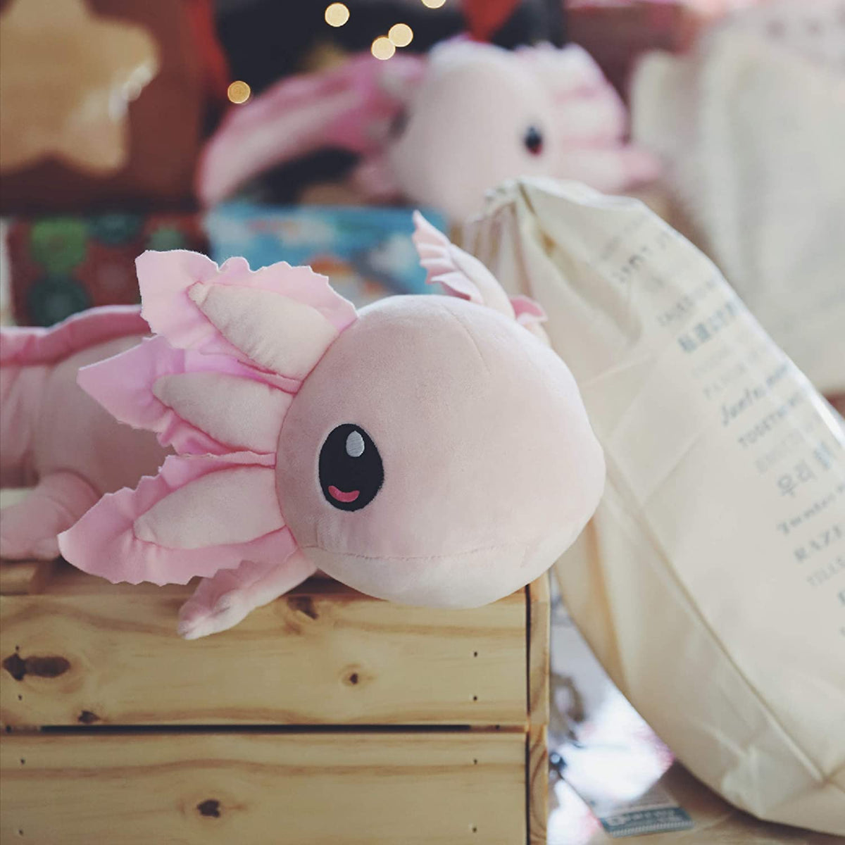 Axolotl plush sitting in wooden crate. 