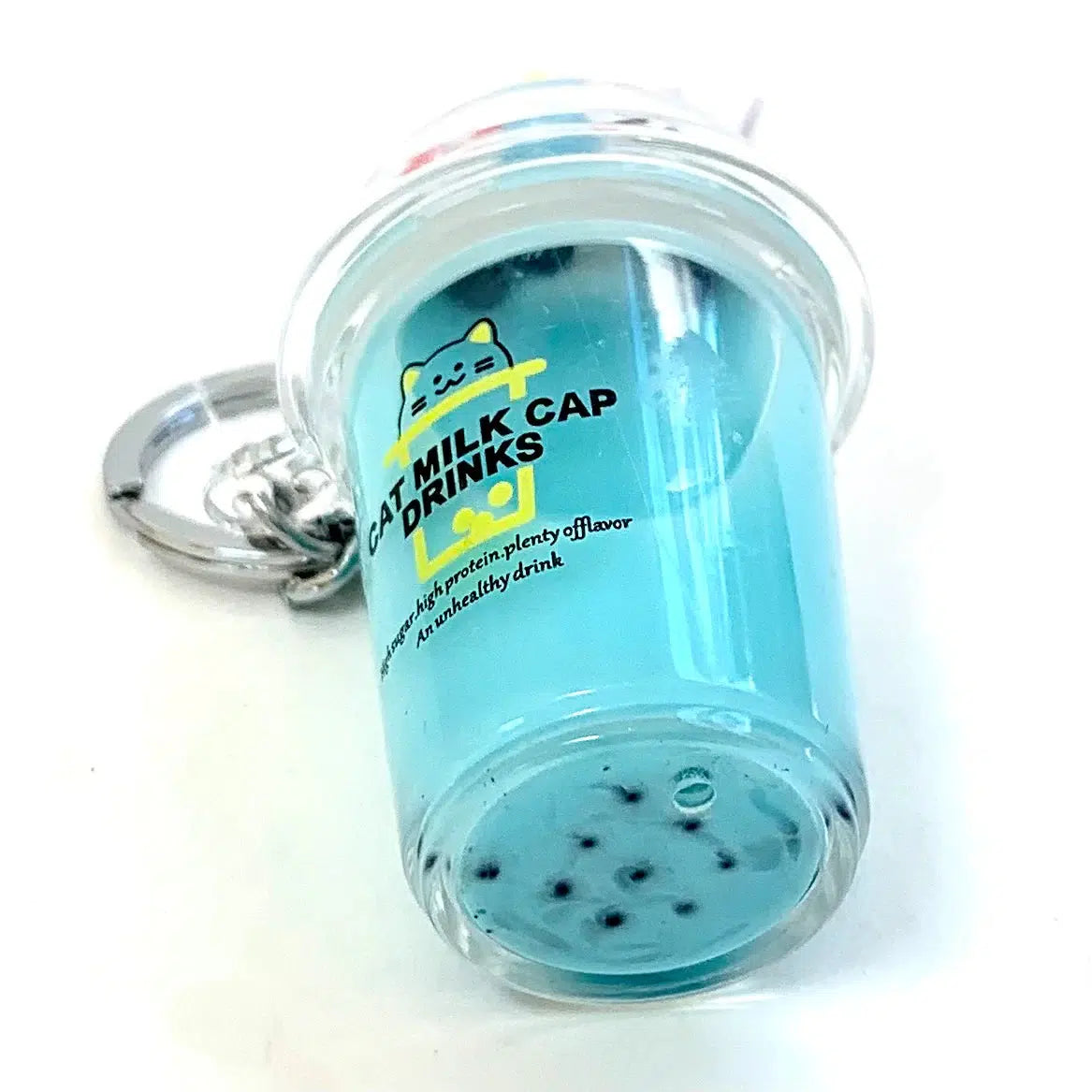 Front view of boba cat with blue liquid laying on its side showing the bobas at bottom of cup.