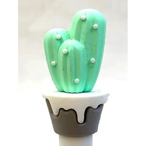 Front view of light green cactus sitting on a brown pot with white top sitting on a gel pen.