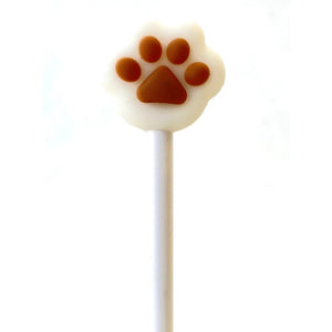 Front view of cream colored cat paw with brown pads sitting on top of white gel pen.