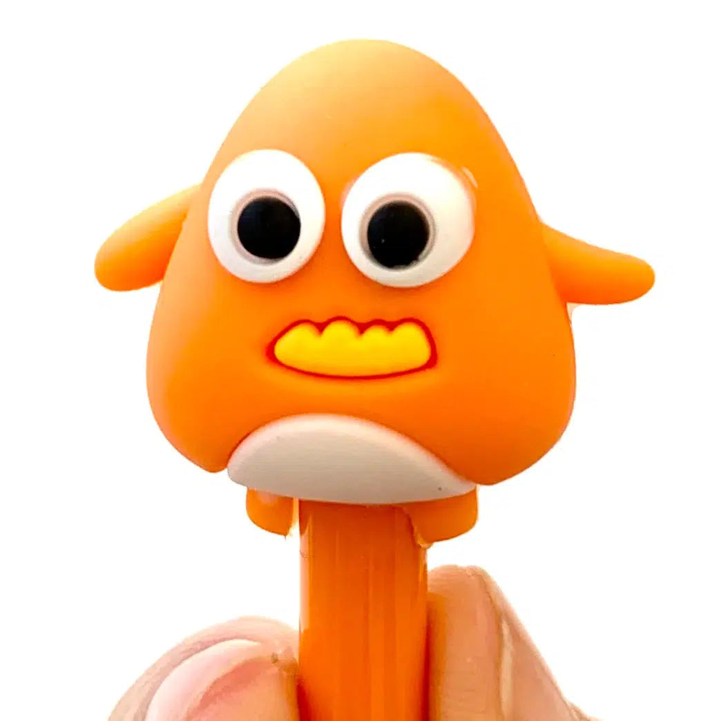Front view of the orange with a yellow mouth Cute Little Monster pen being held between a person&#39;s finger and thumb.