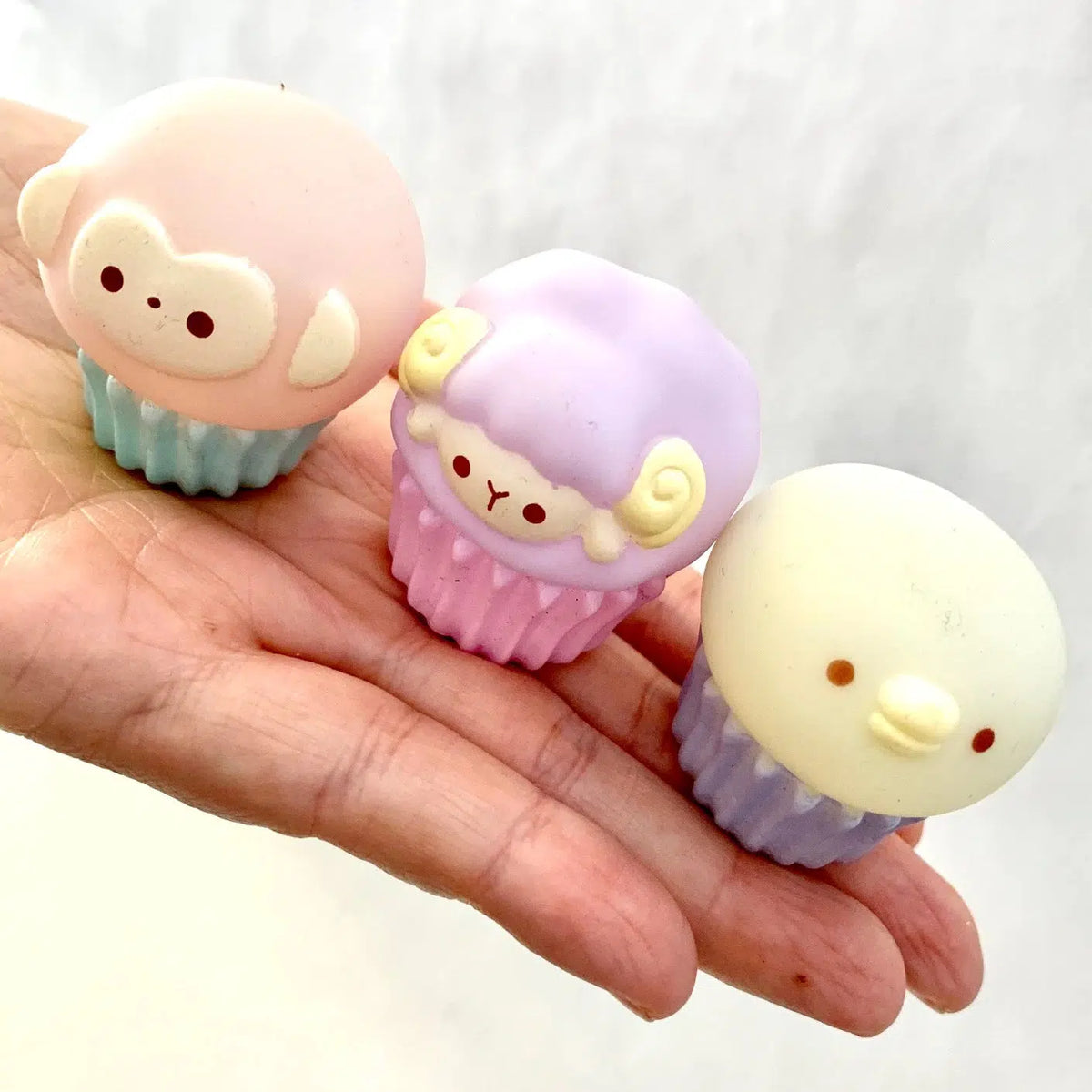 Front view of three different style of animals on three different colored cupcake tins.