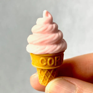 Front view of a person's fingers holding a peach colored Ice Cream Eraser.