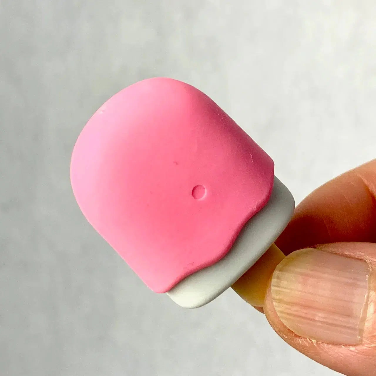 Front view of fingers holding the pink Ice Cream Eraser.