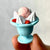 Front view of a person's fingers holding a strawberry sundae from the Ice Cream Erasers.