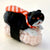 Black cat sitting on a sushi rice ball with an orange and white striped tie on his neck and laying on his back.
