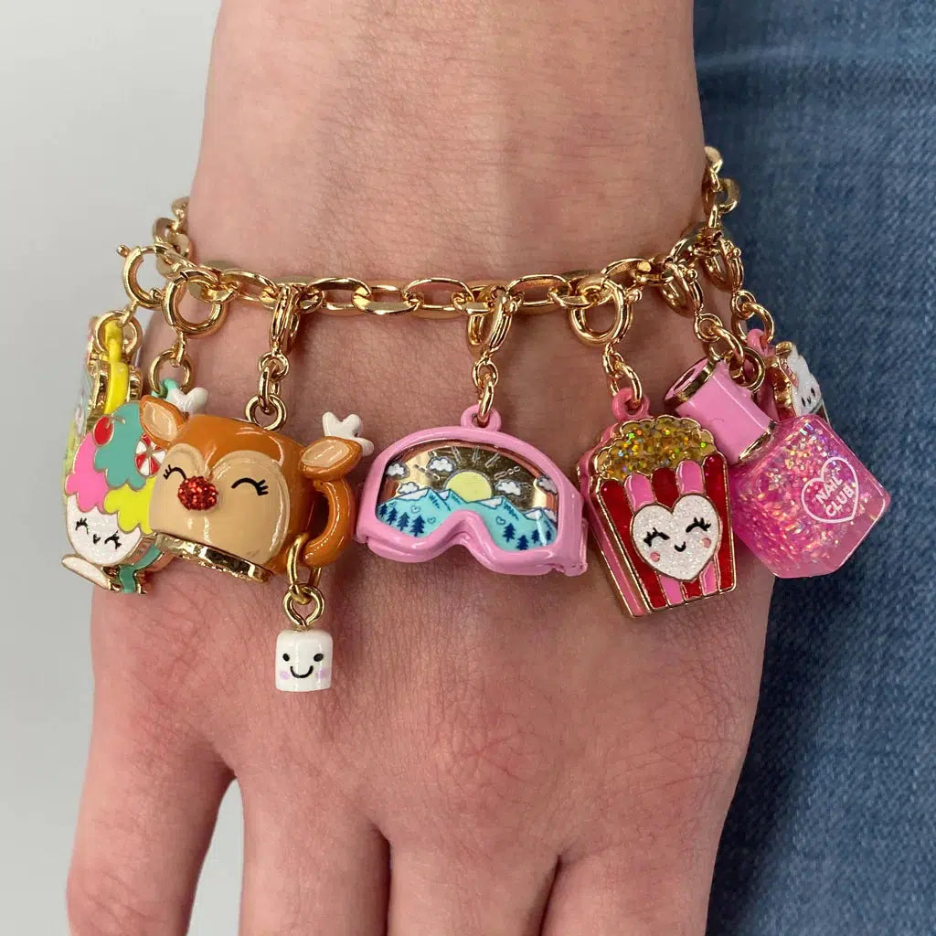 Front view of a person wearing a charm bracelet with the Gold Glitter Nail Polish Charm on it.