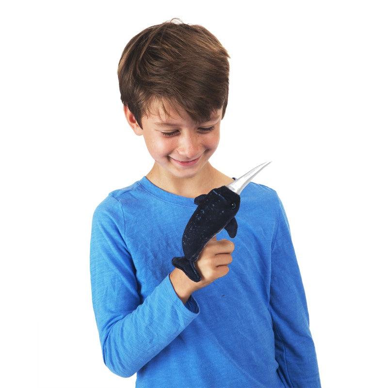 Front view of a mini narwhal finger puppet  on a boys finger.