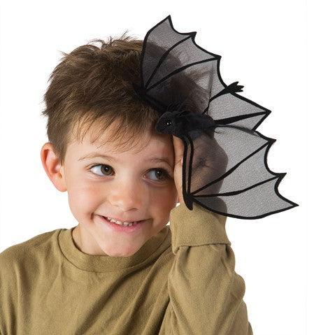 boy with hand on side of head with mini bat on finger